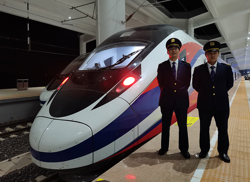 劉銀能（右一）與中國(guó)師父鄔俊鴻在動(dòng)車組前合影。受訪者供圖