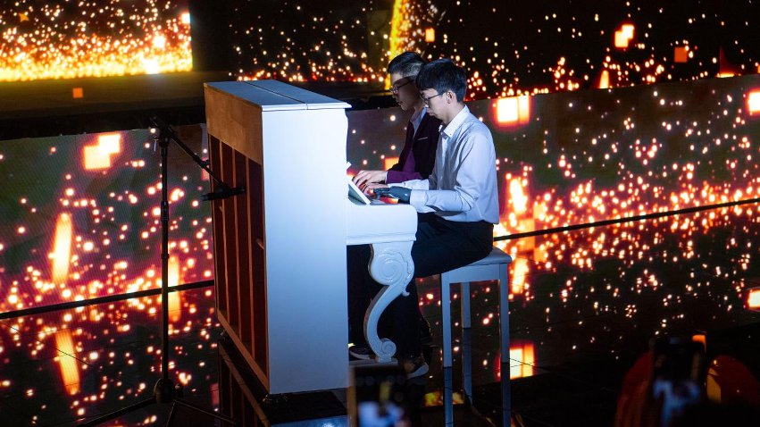 智能仿生手使用者古月與少年鋼琴家舒海峰合奏。主辦方供圖